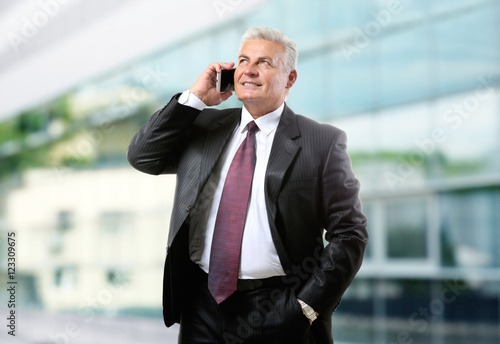 Businessman talking on phone on blurred building background. Lawyer and notary concept.
