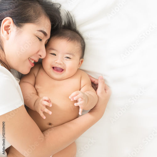 happy family.asian  mother playing with her baby in the bedroom.
