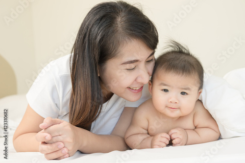 happy family.asian  mother playing with her baby in the bedroom.