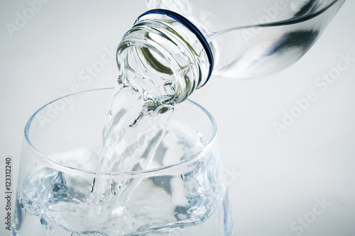 Pouring water on glass on white background