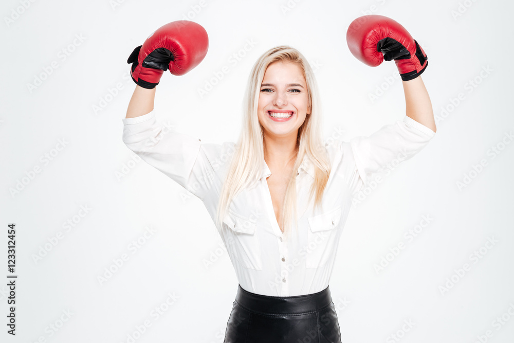 Cheerful young businesswoman in boxing gloves with raised hands Cheerful young businesswoman in boxing gloves with raised hands