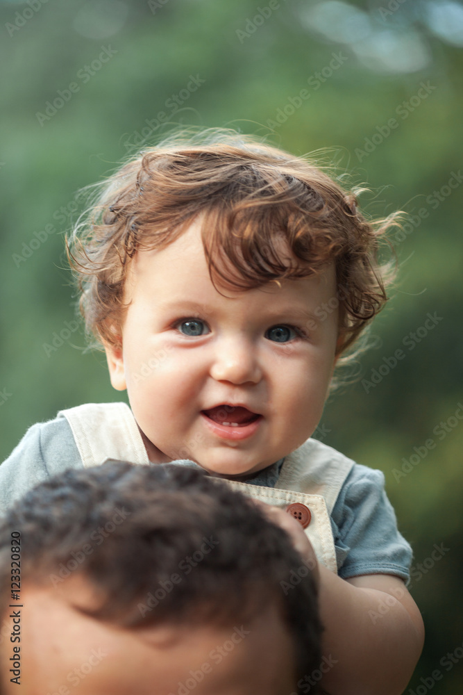 Young beautiful father and little toddler son against green trees Young beautiful father and little toddler son against green trees