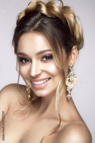 Beautiful woman portrait with plait on head. Young lady posing on grey background. Glamour make up and hairstyle.