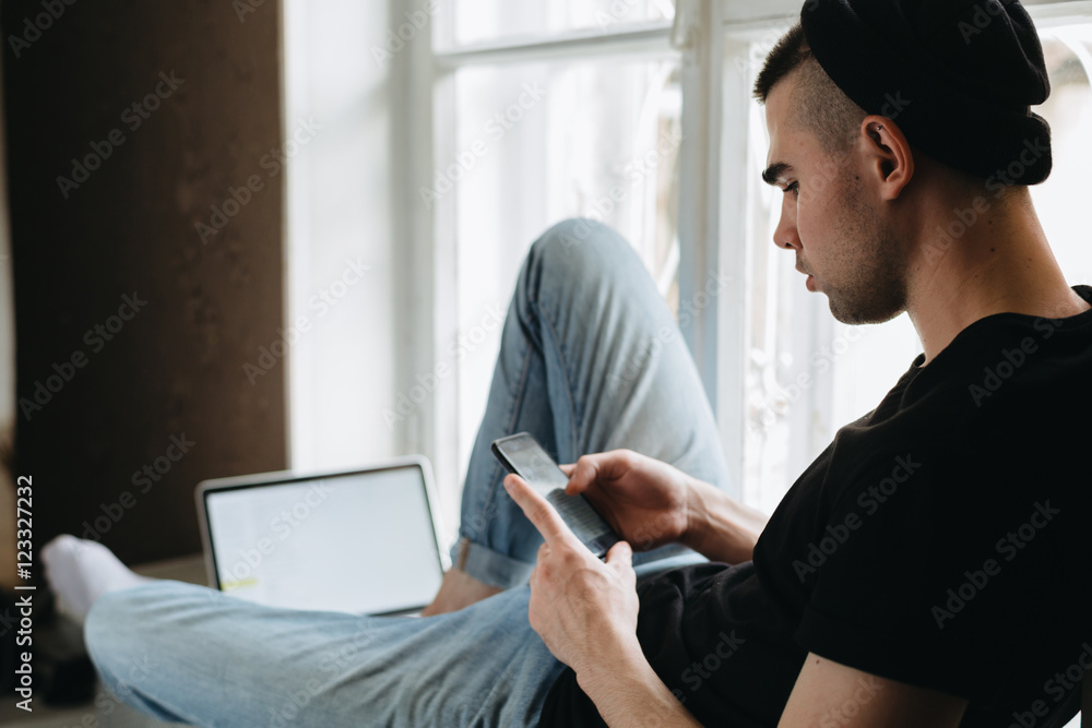 Young male in black beanie typing something on his phone Young male in black beanie typing something on his phone