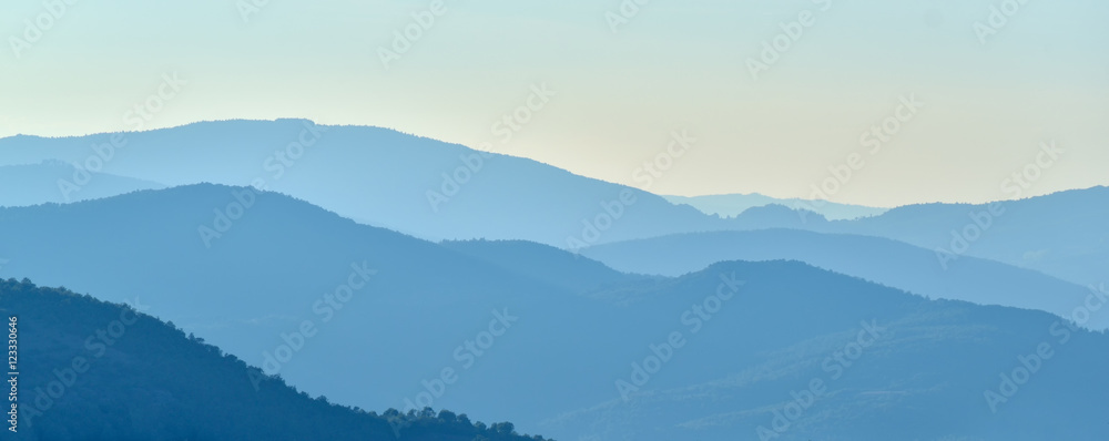 Blue shades on mountains at the horizon in the rays of sunlight at sunset Blue shades on mountains at the horizon in the rays of sunlight at sunset