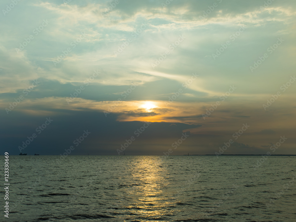 Sunset or sunrise over the ocean with some ship near the peer.