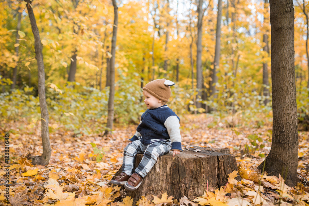 Fototapeta premium Beautiful baby boy one years old crawling in fallen leaves - autumn scene