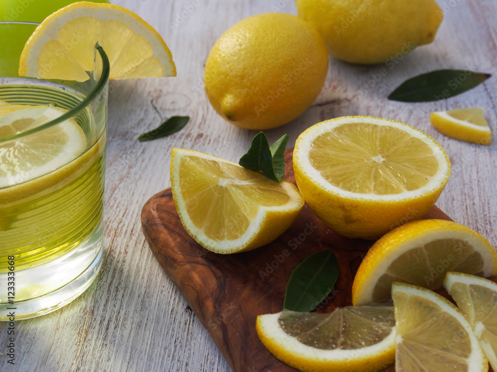 Fresh lemons on a cutting board placed on a wooden table. In the foreground one lemon cut in half. Fresh lemons on a cutting board placed on a wooden table. In the foreground one lemon cut in half.