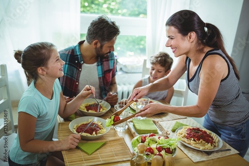 Smiling woman serving meal to her family