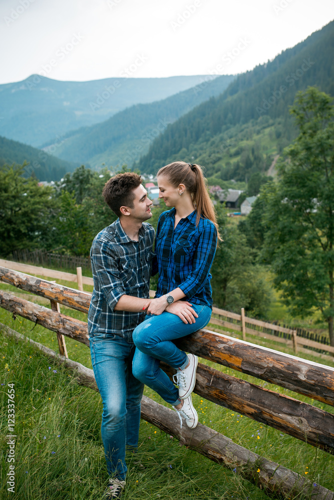 Guy and girl lovers tourists relax and admire beautiful mountain scenery
