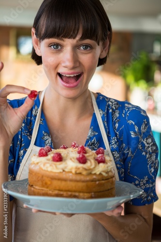 Excited waitress holding a cake and a cherry
