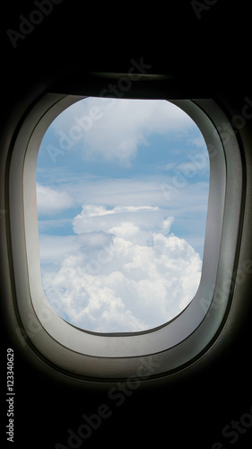 Closeup of the airplane window with the clouds sky background.