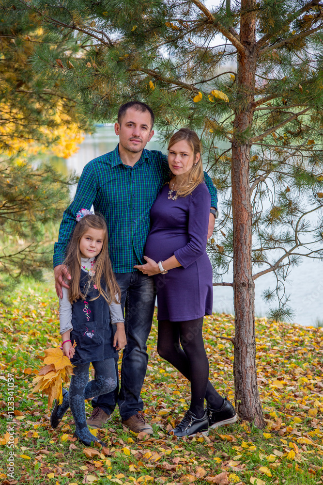 Fototapeta premium Happy pregnant family in autumn nature