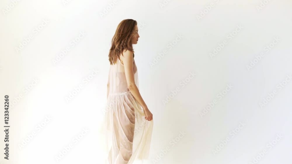 Beautiful young woman dances in front of white wall Beautiful young woman dances in front of white wall