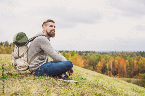 Young man traveler sitting on top of the hill. Travel and active lifestyle concept
