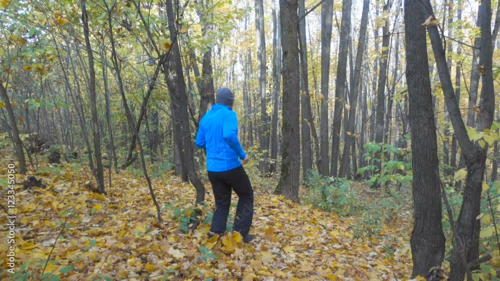 Man jogging cross country running on trail in forest. Training and exercising outdoors when cross country running in inspirational autumn landscape. Sports Motivation. Slow Motion. Man jogging cross country running on trail in forest. Training and exercising outdoors when cross country running in inspirational autumn landscape. Sports Motivation. Slow Motion.