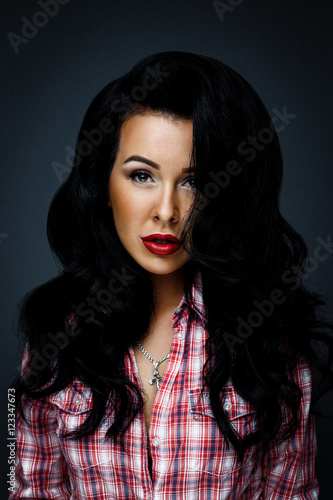 portrait of beautiful young woman in jeans shorts, red checked shirt, red lips