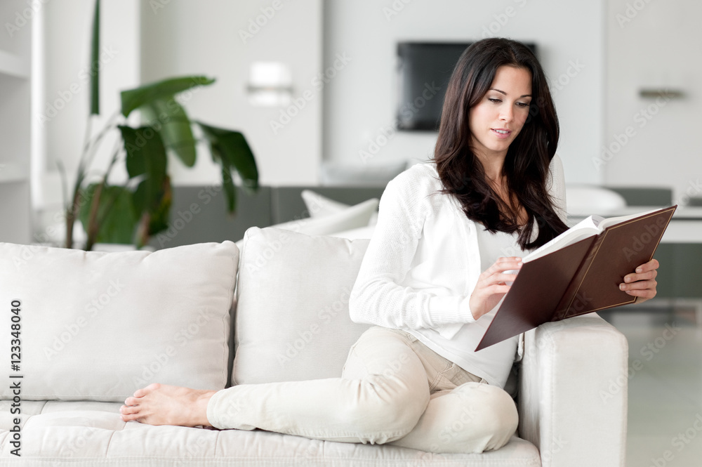 Young Woman Lounging in Living Room Reading Book Young Woman Lounging in Living Room Reading Book