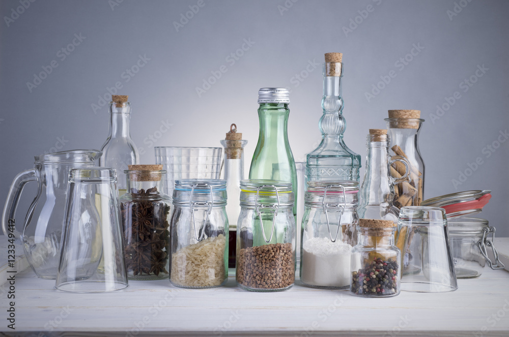 Still life of transparent glass bottles, cans and glasses on a white wooden table. Still life of transparent glass bottles, cans and glasses on a white wooden table.