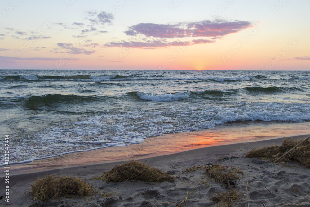 Michigan Summer Beach Sunset Panorama. Sunset horizon reflects off the blue waters of Lake Michigan as waves crash on the beach. Hoffmaster State Park. Muskegon, Michigan.