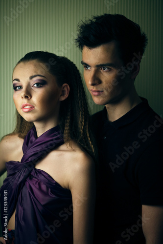 Magnetic girl in violet dress and man in black stand bfore the w photo