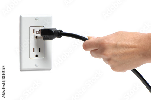 Woman's hand pulling electrical plug from household power outlet isolated on white background
