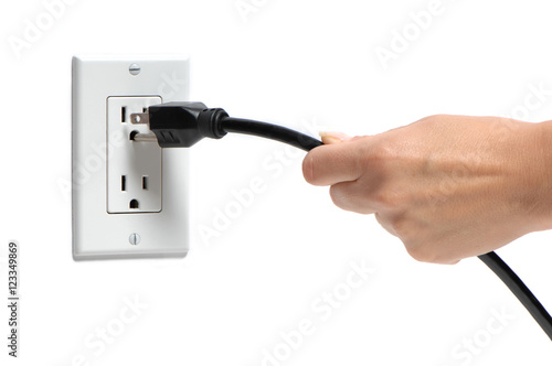 Woman's hand pulling electrical plug from household power outlet isolated on white background photo