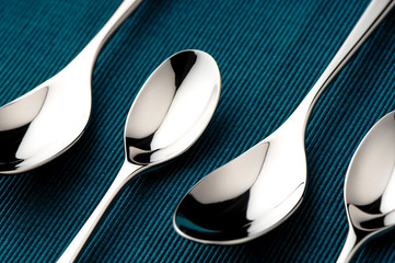 Shiny alternating spoons on a blue Christmas Hanukkah Thanksgiving holiday table