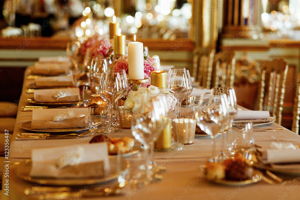 Glassware sparkles on dinner table served in golden and pink ton