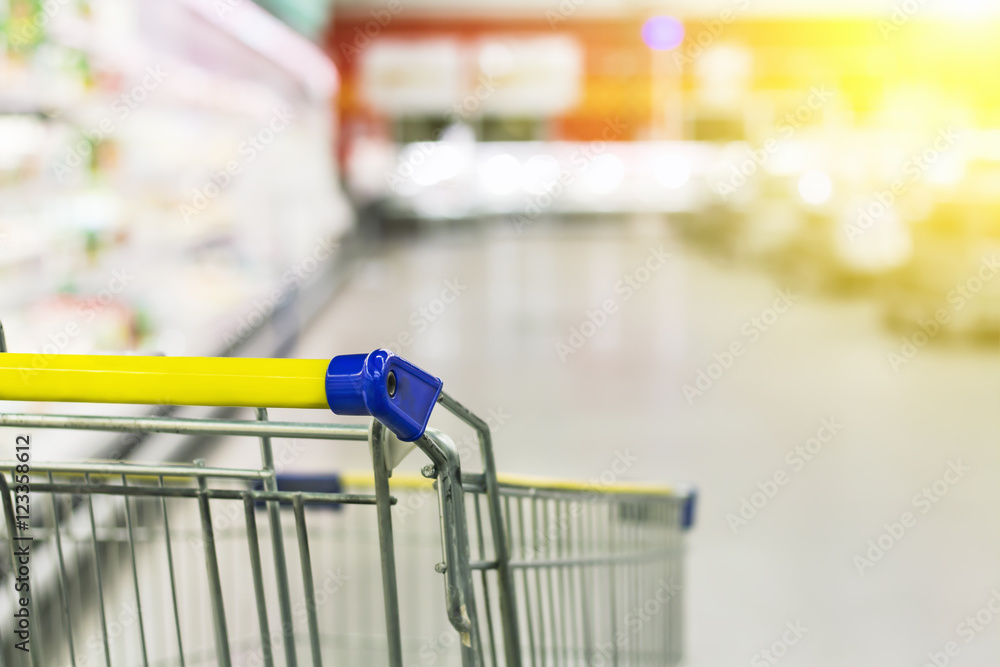 Cart at the grocery store. Abstract blurred photo of store with trolley in department store bokeh background. New ideas in trade and business.Advertising of food products. Shopping at the hypermarket.