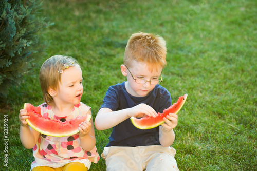 children eating red watermelon on grass