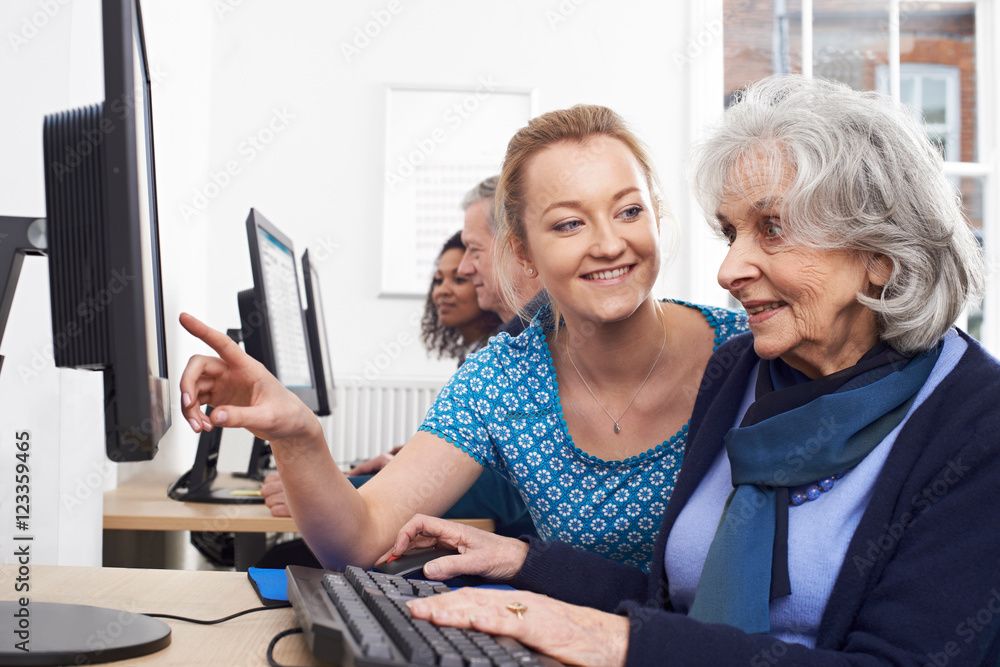 © highwaystarz - Tutor Helping Senior Woman In Computer Class