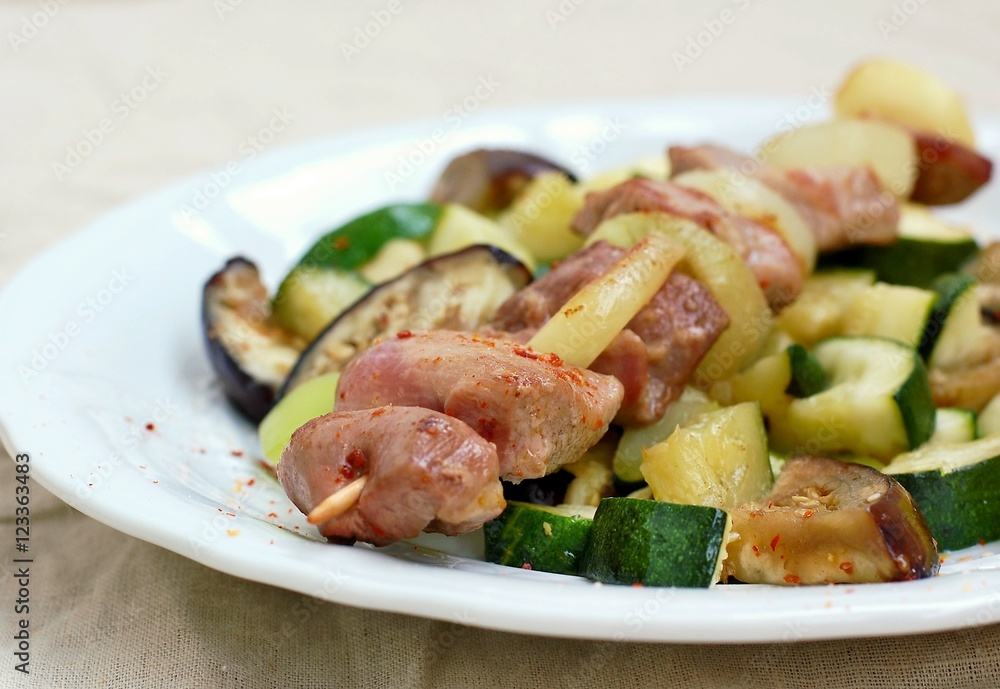 Skewer with roasted turkey hen meat with onion, zucchini and aubergine on white plate Skewer with roasted turkey hen meat with onion, zucchini and aubergine on white plate