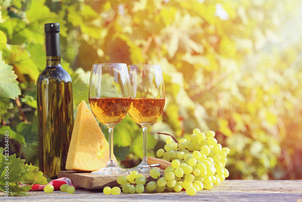 Wine in glasses with bunch of grape and cheese on wooden table