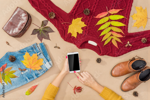 Online shopping concept with female hands searching internet and warm autumn clothes