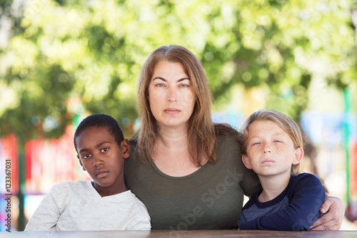 Serious mom sitting with sons at park table