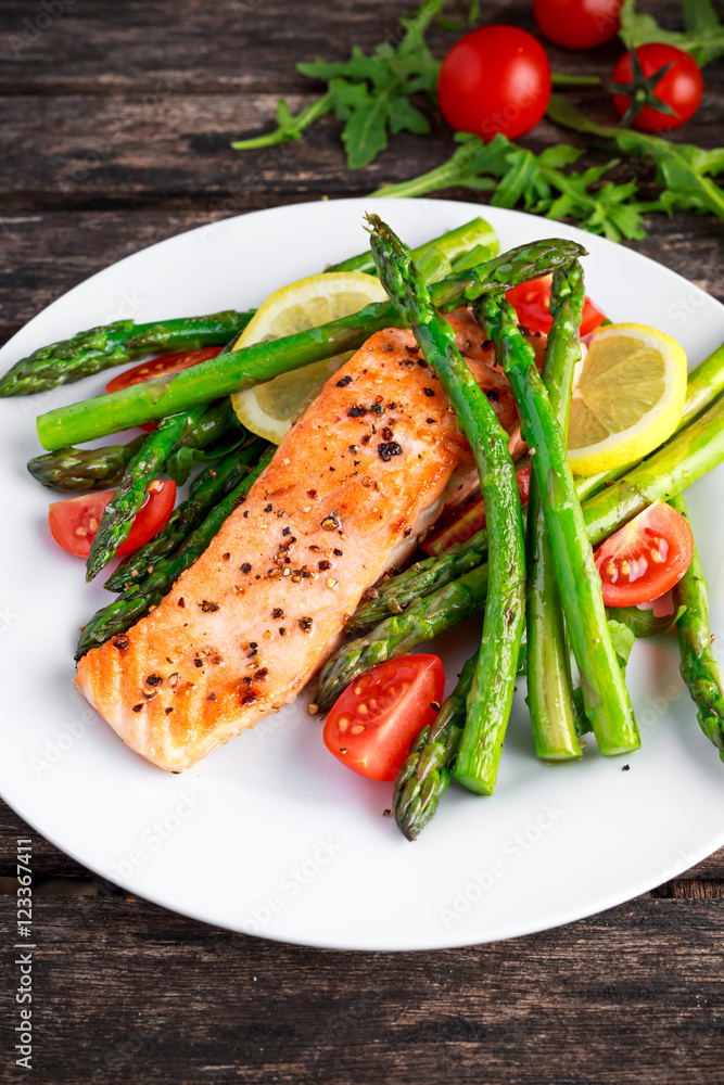 Fried salmon with asparagus, tomatoes, lemon, yellow lime on white plate Fried salmon with asparagus, tomatoes, lemon, yellow lime on white plate