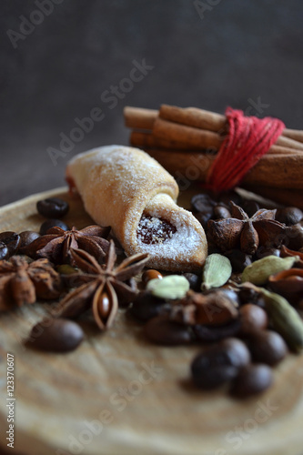 Winter treat. Rolled shortbread cookie, bunch of cinnamon sticks, coffee beans,flavors,anise stars, cardamom on rustic wooden tray. Christmas dessert. Shallow depth of field.
