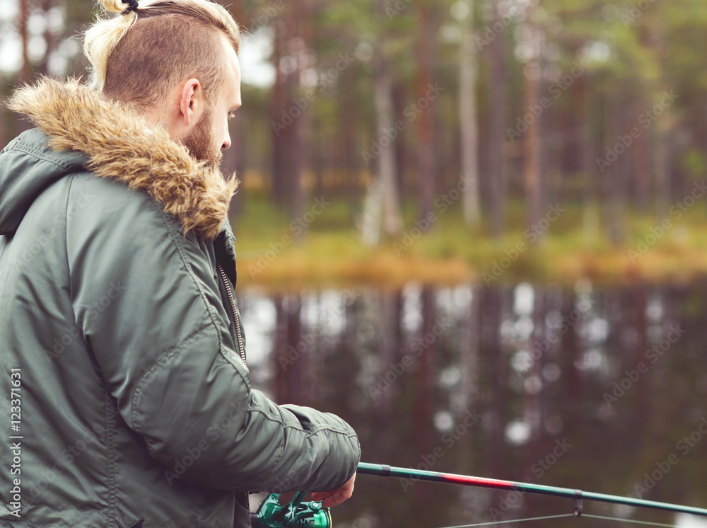 Fototapeta premium Hipster fisherman with a spinning rod catching fish