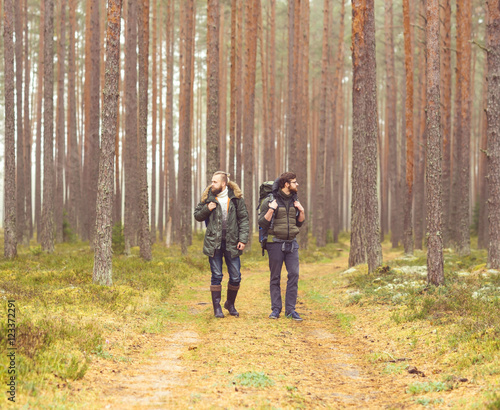 Man with a backpack and beard and his friend in forest © Acronym