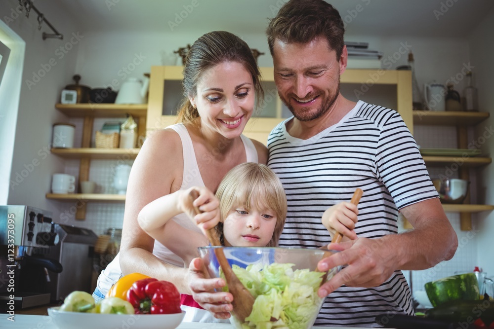 Parents watching their daughter mixing the salad Parents watching their daughter mixing the salad