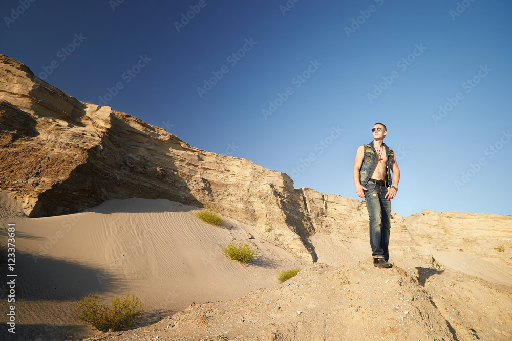 Portrait of a man in denim clothes on the sand. Portrait of a man in denim clothes on the sand.