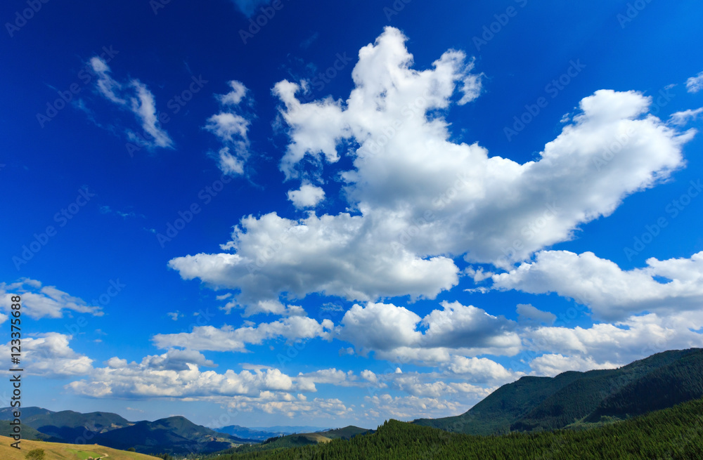 Blue sky with white clouds over mountain.