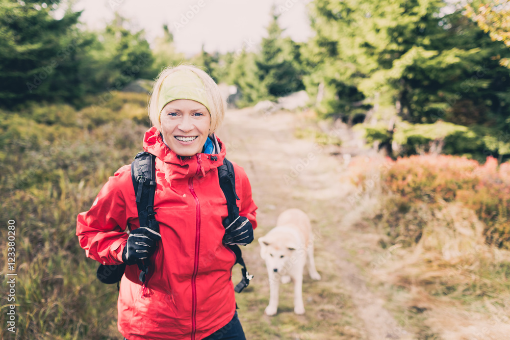 Happy woman hiking walking with dog in autumn forest, sunny day in woods Happy woman hiking walking with dog in autumn forest, sunny day in woods