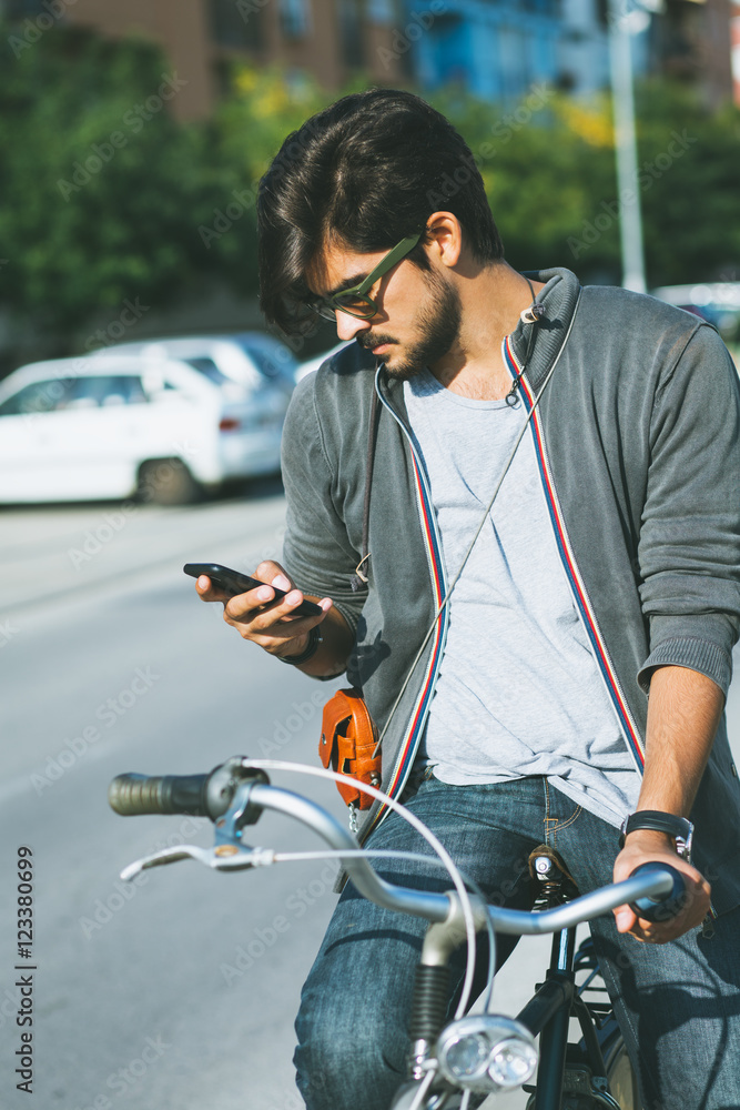 Young handsome guy with a bicycle on street looking at mobile phone. Young handsome guy with a bicycle on street looking at mobile phone.
