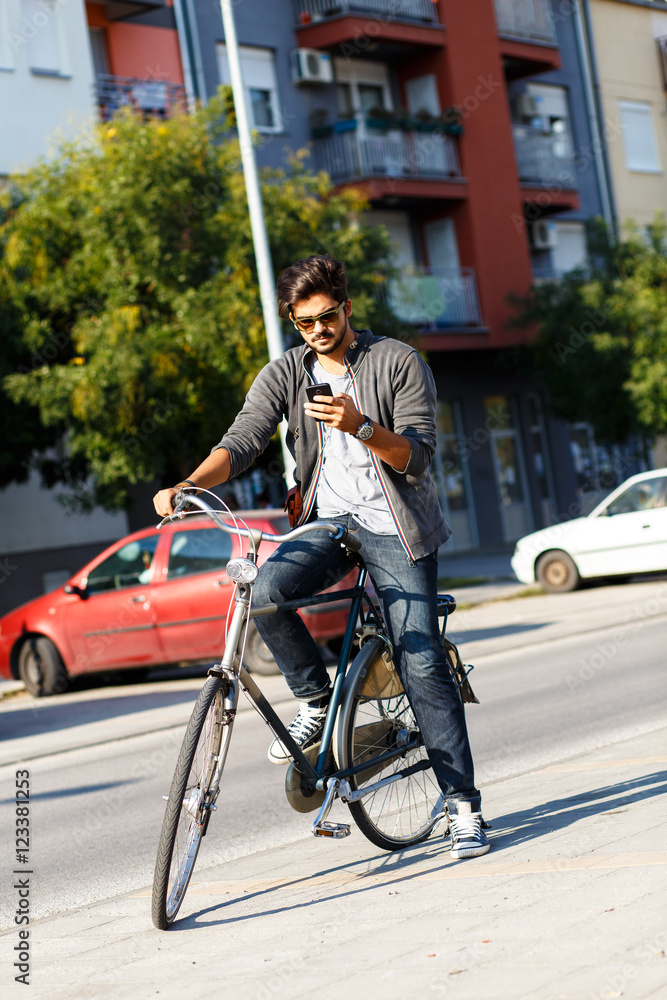 Young handsome guy with a bicycle on street looking at mobile phone. Young handsome guy with a bicycle on street looking at mobile phone.