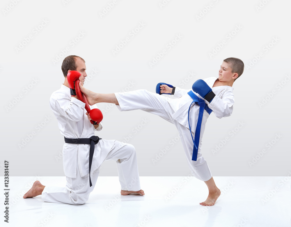 Coach keeps makiwara in their hands on which beats the boy Coach keeps makiwara in their hands on which beats the boy