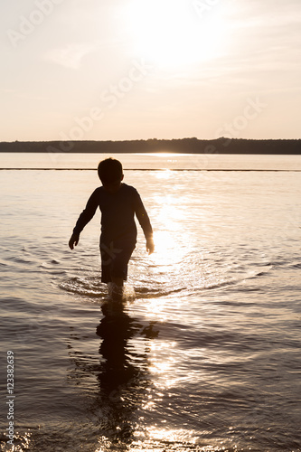 Silhouette of young boy wading in water