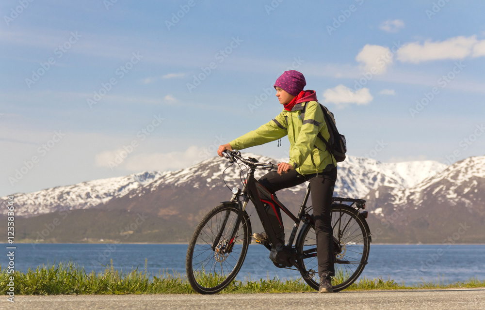 Fototapeta premium junge Frau sitzt auf Fahrrad vor Bergkulisse