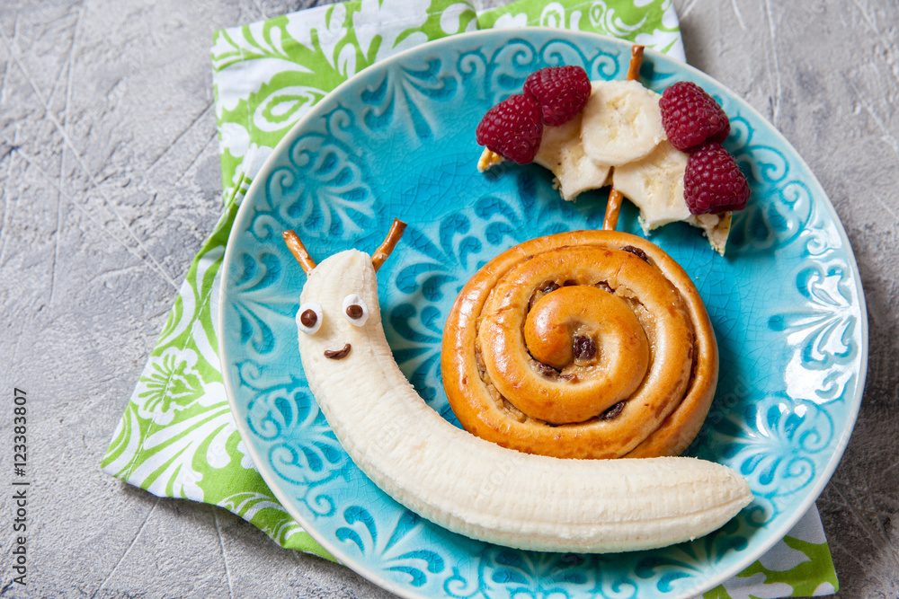 Fun food. Cinnamon bun with banana look like a snail Fun food. Cinnamon bun with banana look like a snail